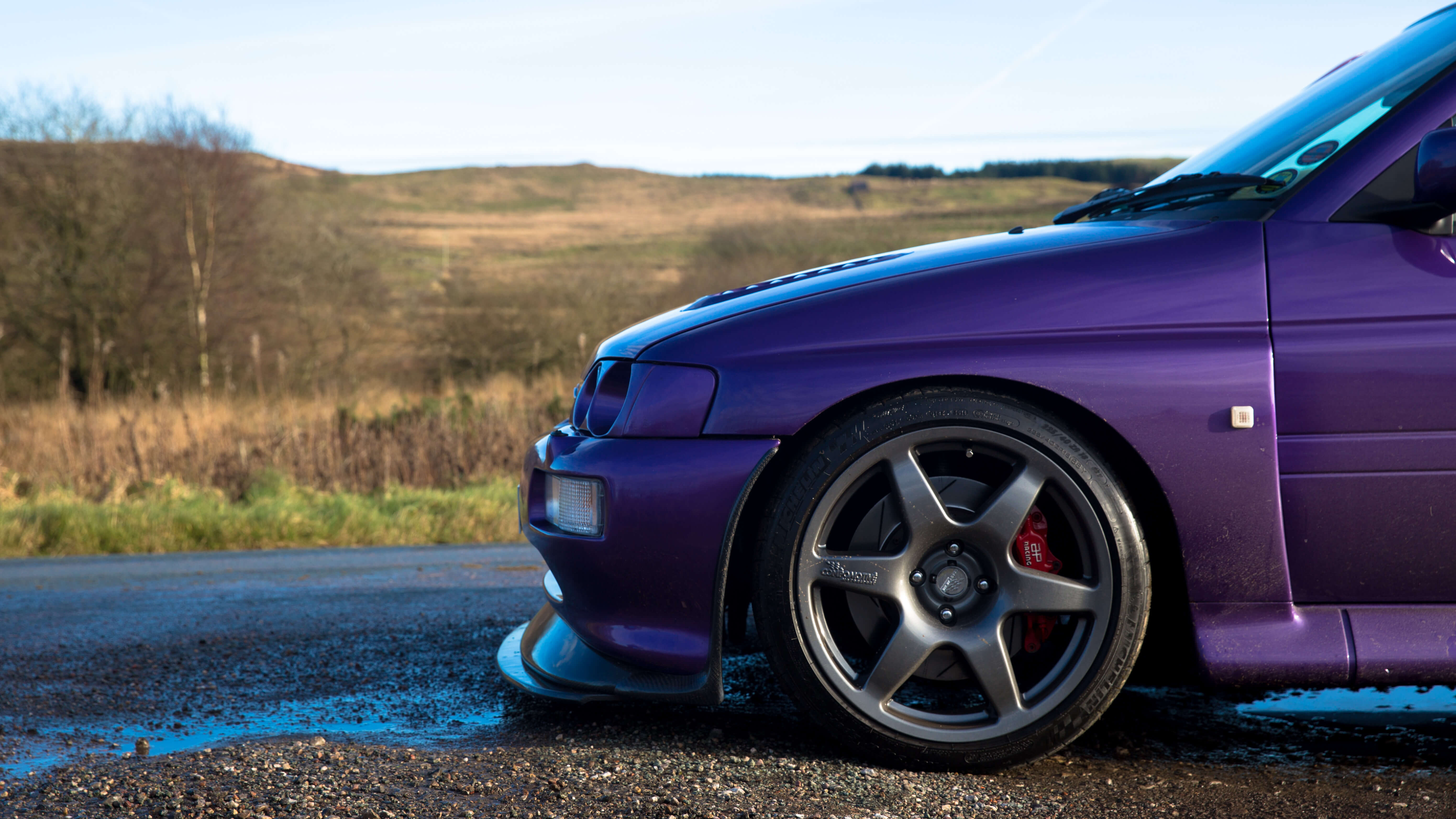 Front of purple Escort Cosworth with landscape in the background