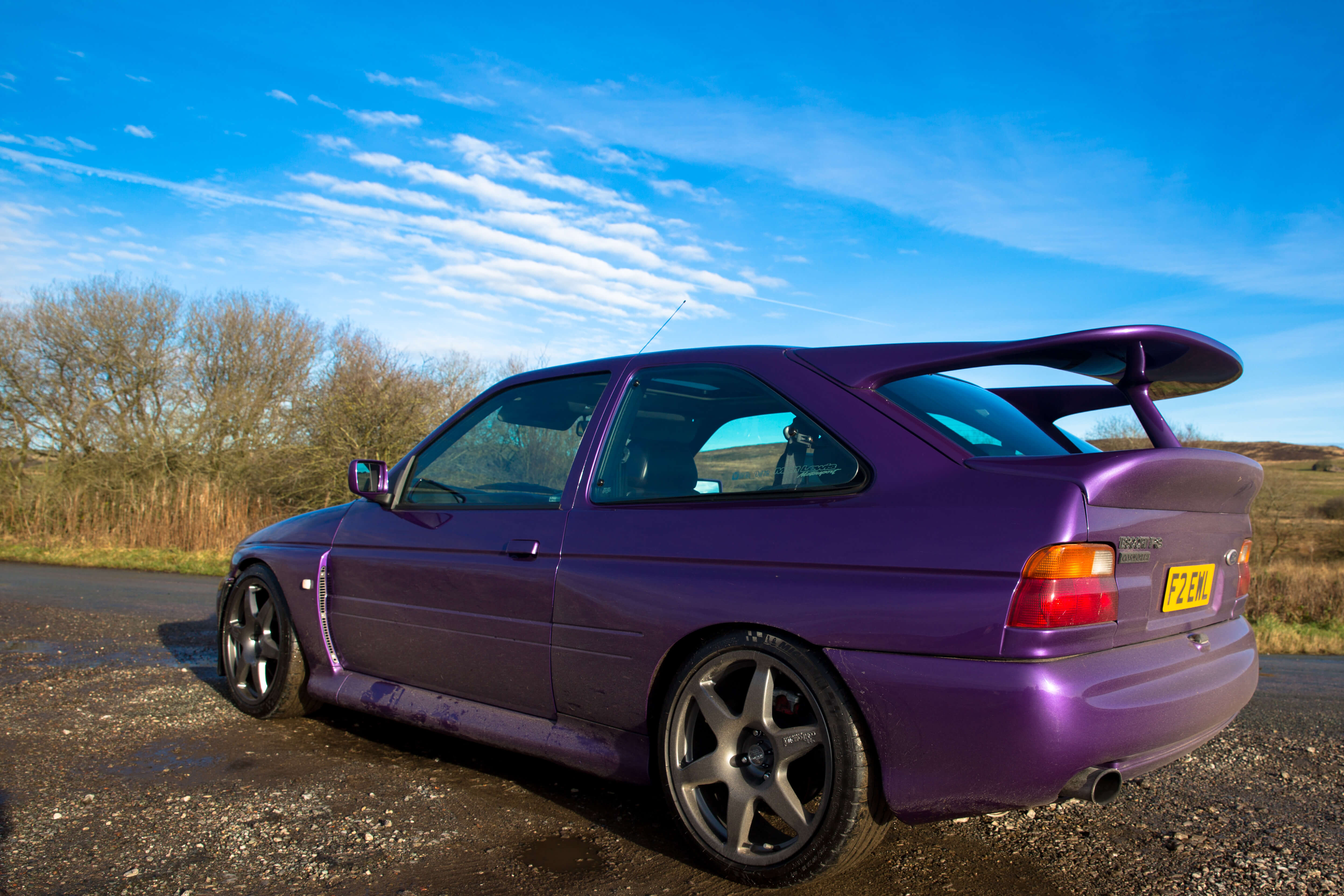 Purple Escort Cosworth shown from the back with blue sky in view