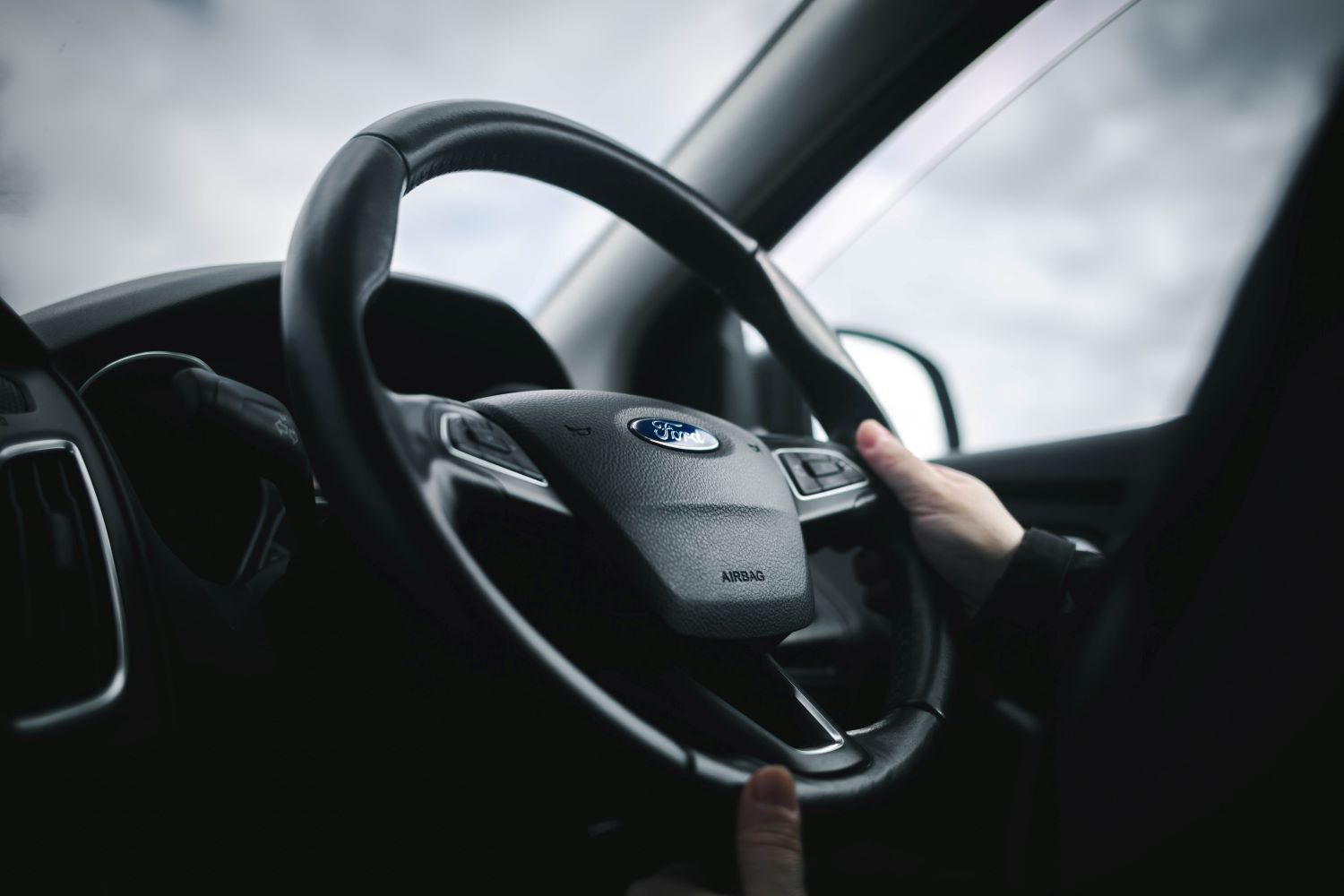 Close up of steering wheel with person's hand resting on the wheel