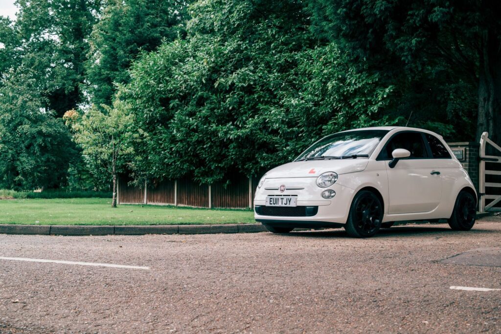 Fiat 500 with learner driver plates parked outside with trees in the background