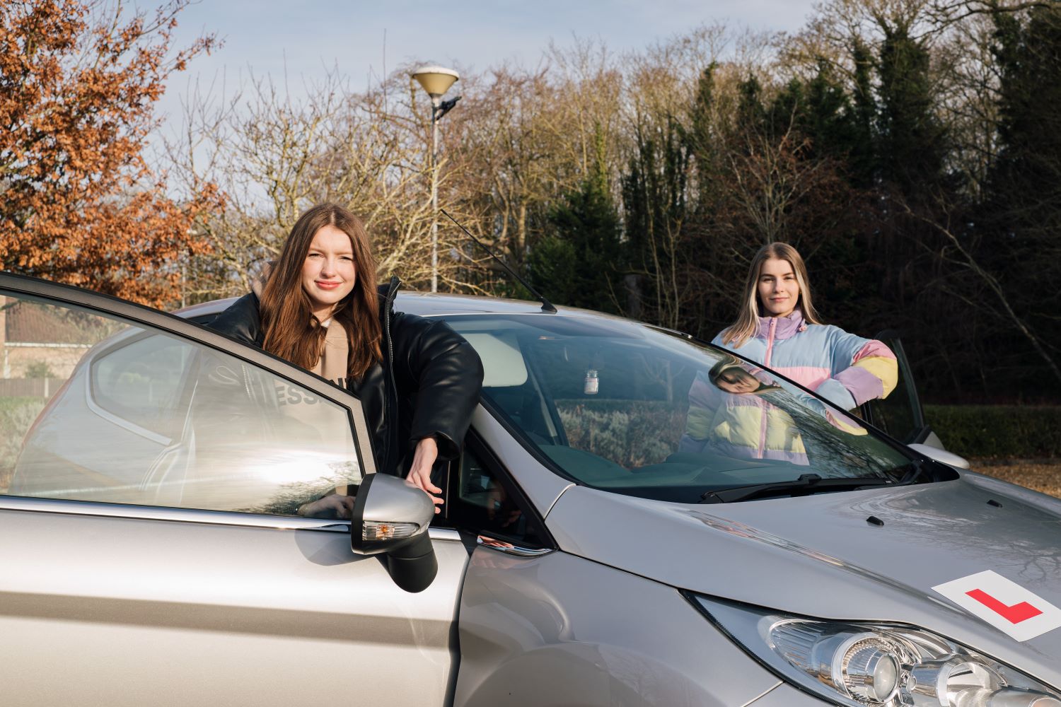 Two young women outside car with L plate