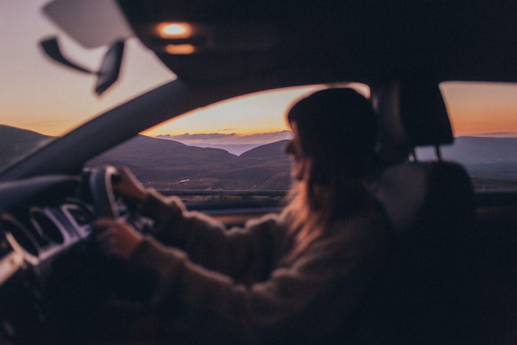 Woman driving car with sunset in the background