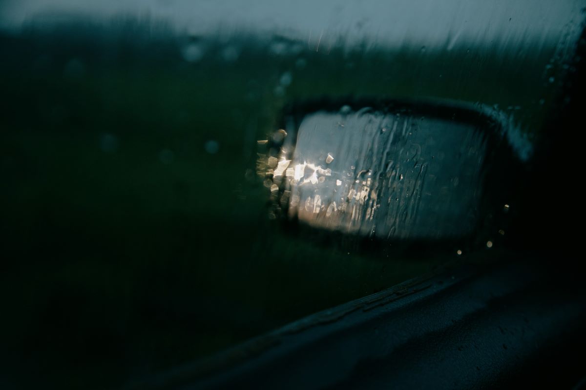 View of side mirror from rainy car window
