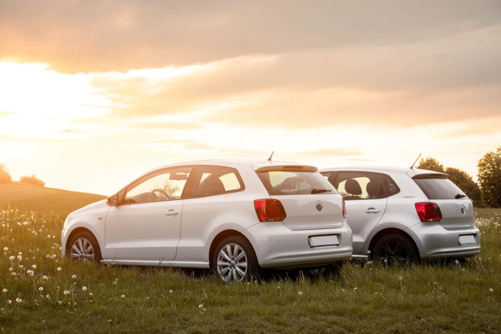 Two VW Polos in a grassy field with the sunset in the background