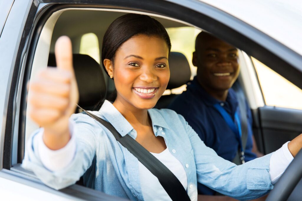 Woman in car smiling at the camera with thumbs up