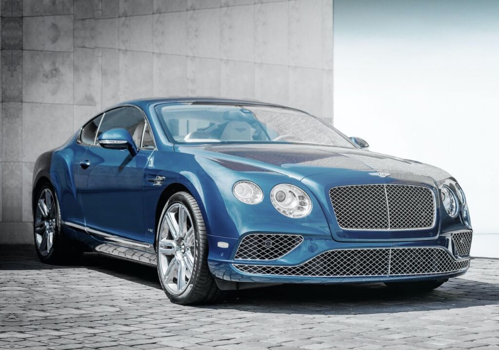Blue Bentley Continental GT car parked in front of grey wall