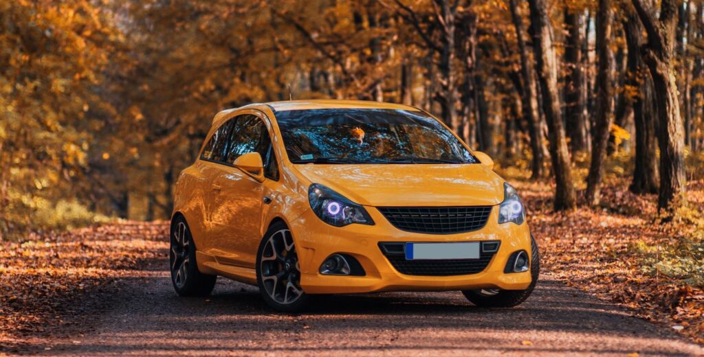 Orange modified Vauxhall Corsa with autumn trees in background