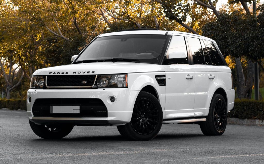 White modified Range Rover parked outside with trees in the background